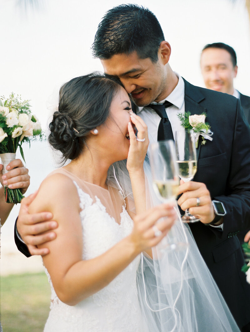 Photo of couple with champagne glasses cuddling and laughing after a toast with  friends.