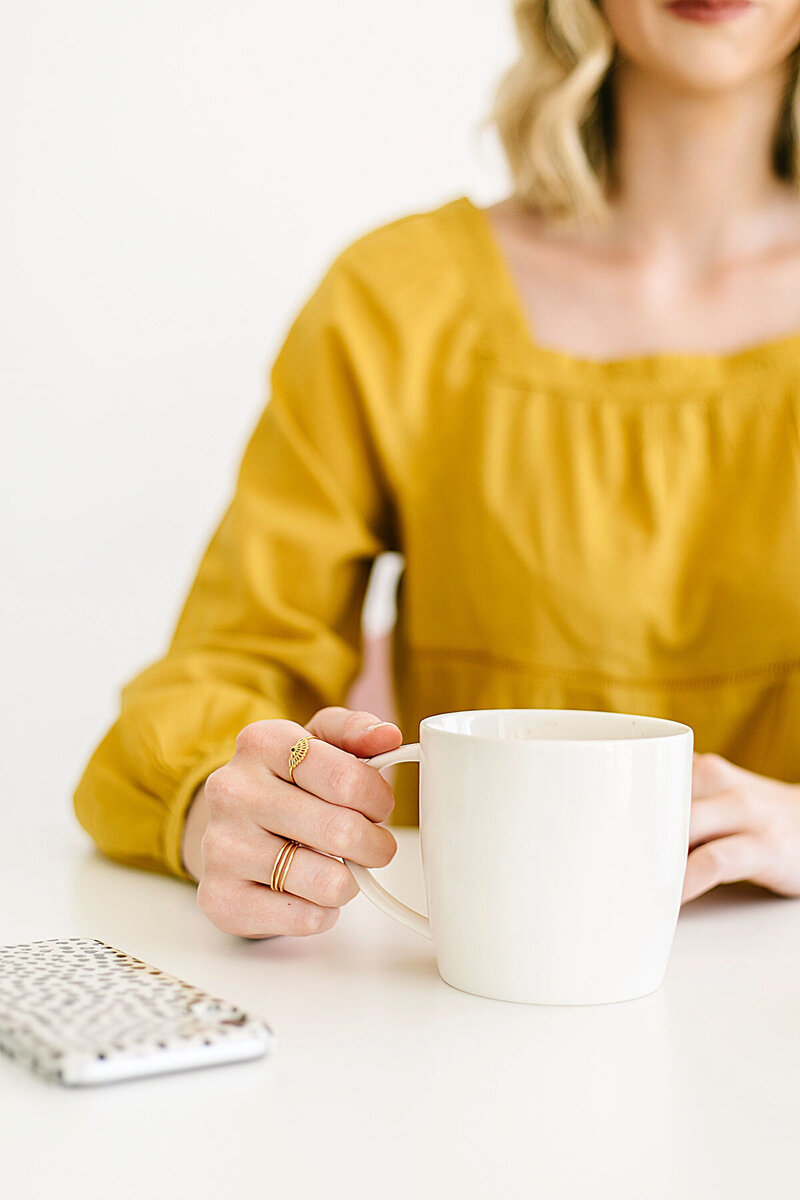 a lady in a yellow top is  drinking coffee