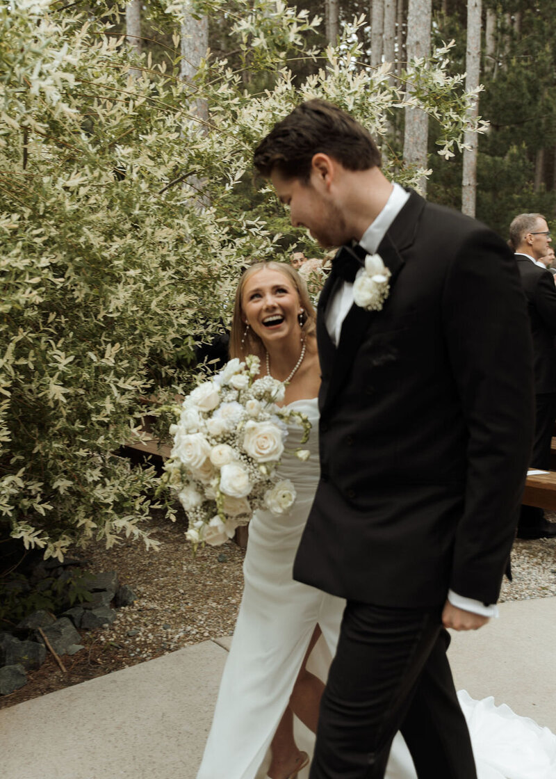 bride and groom smiling as they walk down the isle of their outdoor wedding 