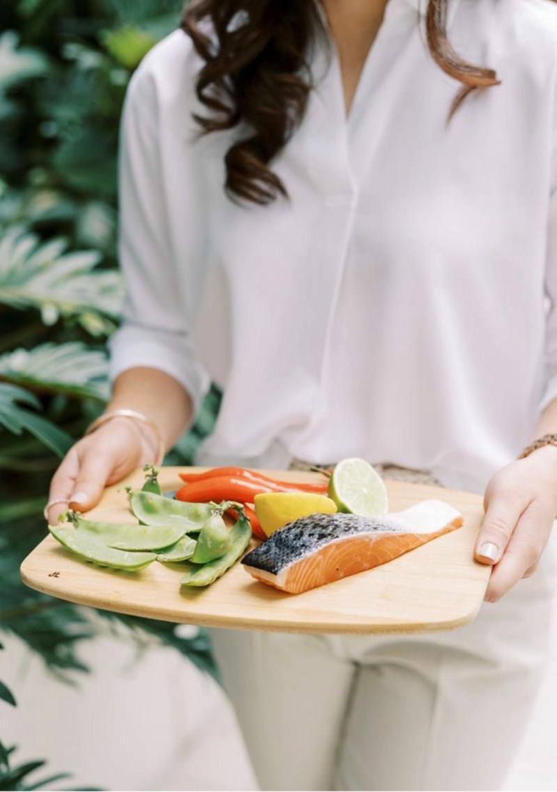 Dietitian presents a platter of fresh avocado, fish, and fruits, emphasising nutritious choices for gut health.