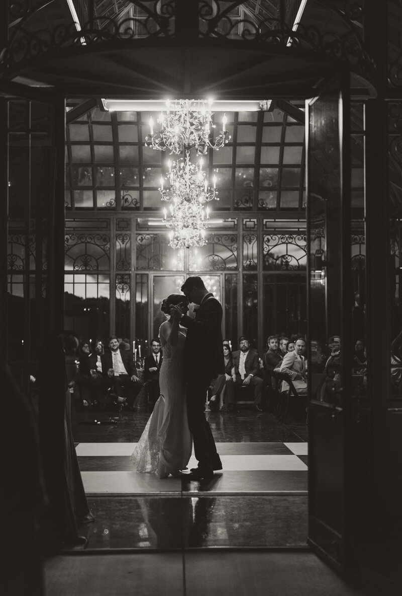 Bride and groom share their first dance beneath chandeliers in the Solarium at The Little Chapel at Haven Ridge, Winston-Salem NC.