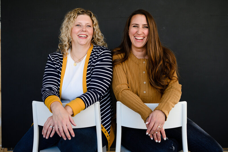 Women in business podcast shows hosts Lisa and Sarah sitting on chairs.
