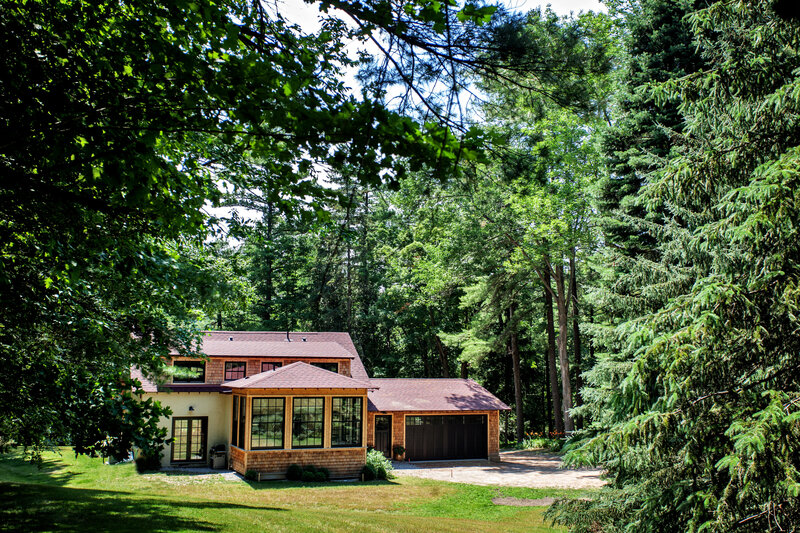 A house in a forest with a sunroom and a garage