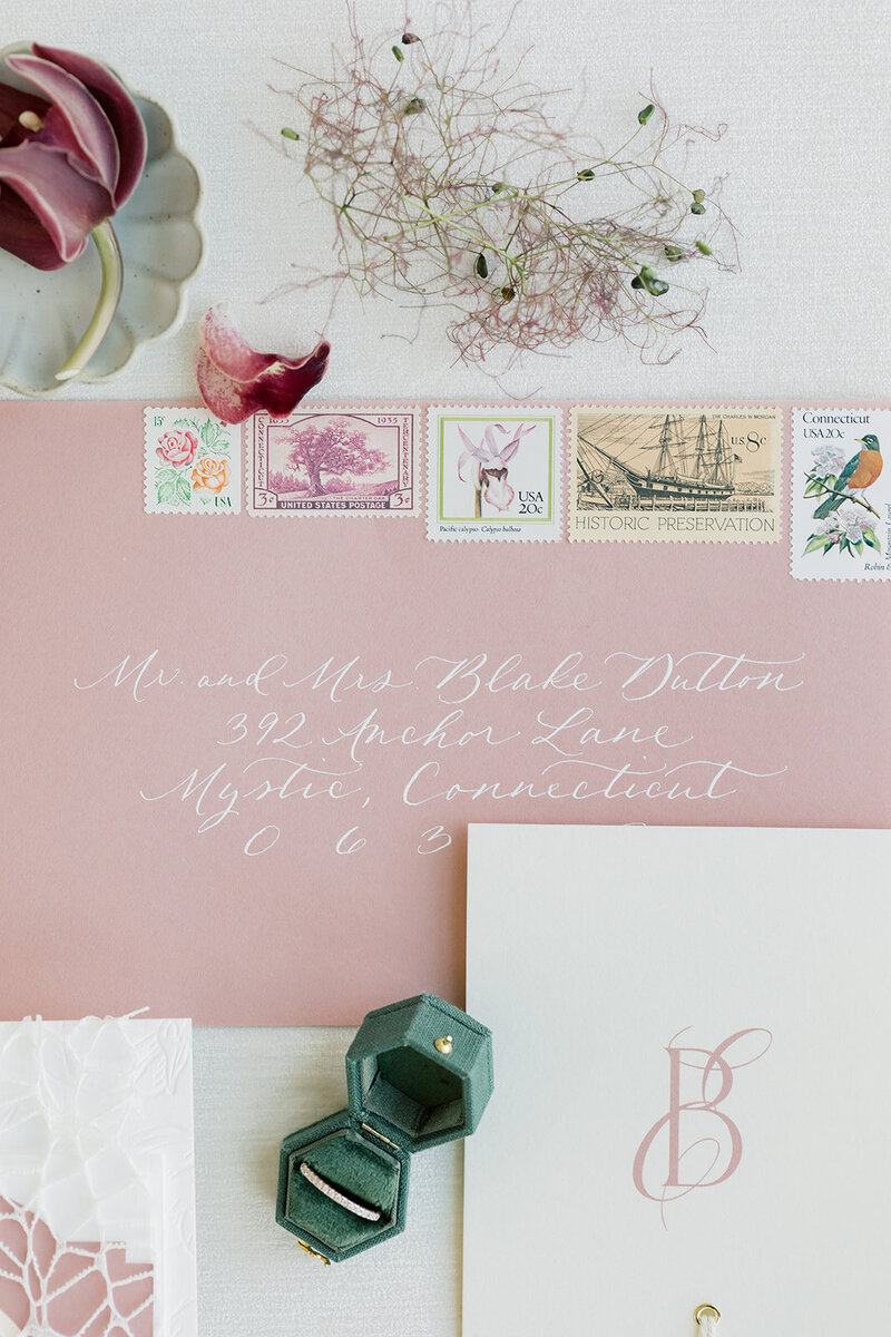 Dusty rose envelope with white ink calligraphy and vintage postage for Mystic, Connecticut wedding.