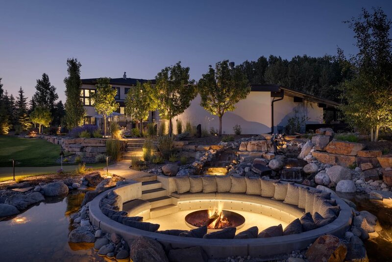 An oversized backyard firepit with custom cushions and outdoor accent lighting. 