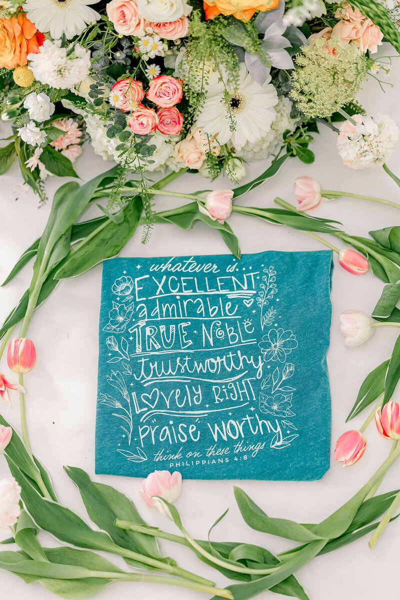 Teal t-shirt with writing and tulips surrounding it 