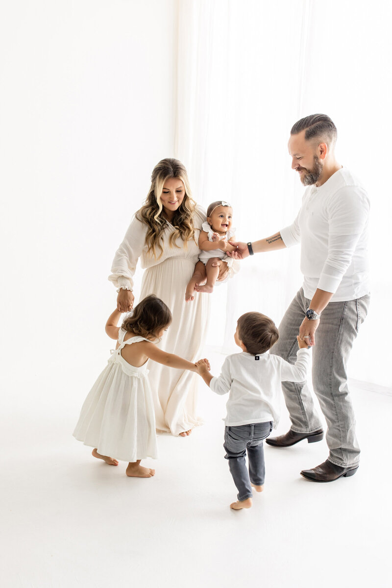 family of five holding hands in natural light studio