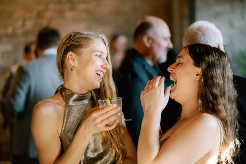 Two bridesmaids laugh during the cocktail hour