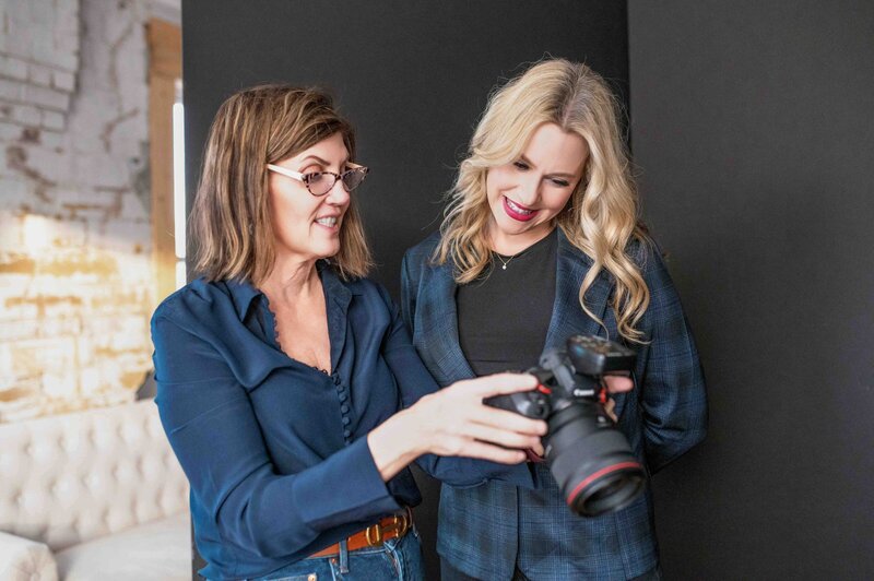 ✅ Alt Text: Photographer Carolyn Vaughn showing a client branding portraits on a camera screen during a session in a stylish salon.

