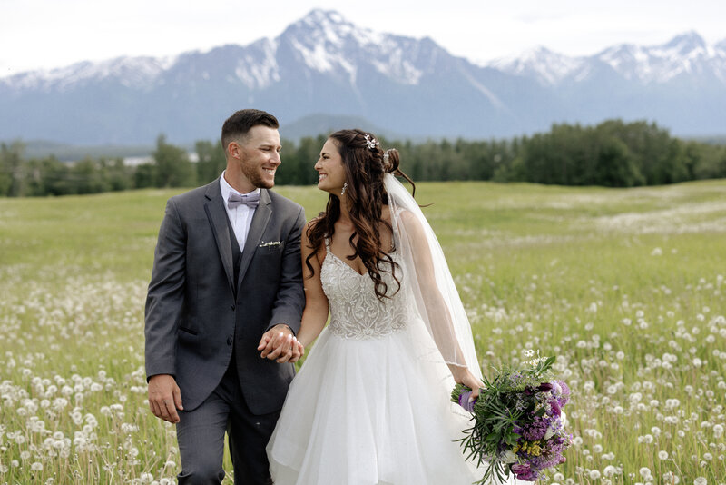 A couple standing together holding a bouquet of flowers after their wedding ceremony. 