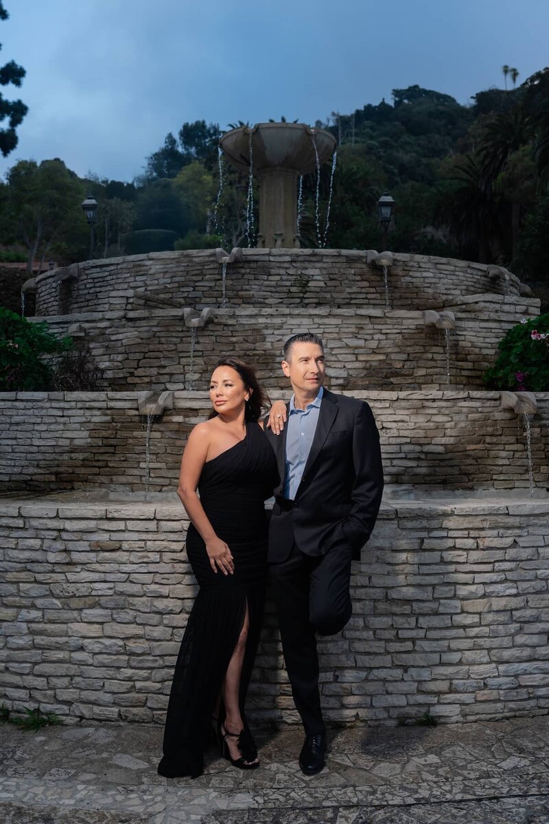 Couple pose elegantly in front of tiered stone fountain during their Malaga Cove engagement session in Palos Verdes
