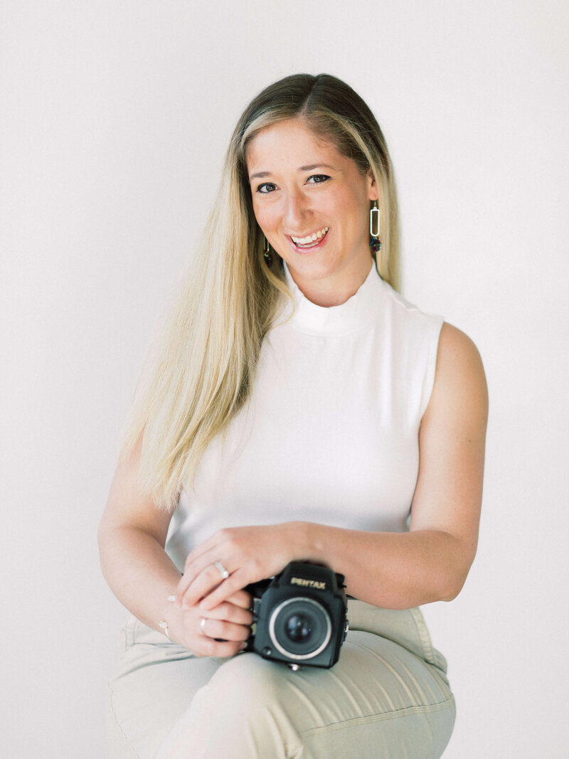 Erin Winter is an award winning Washington DC Wedding and Family Photographer and is posing for a photograph with her camera