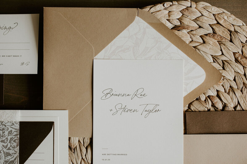 White wedding invitation with script font and tan envelope