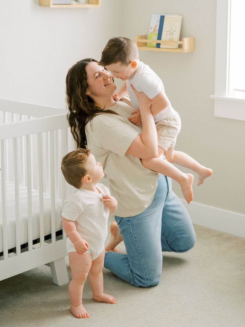Mother holding a toddler with a baby standing beside them
