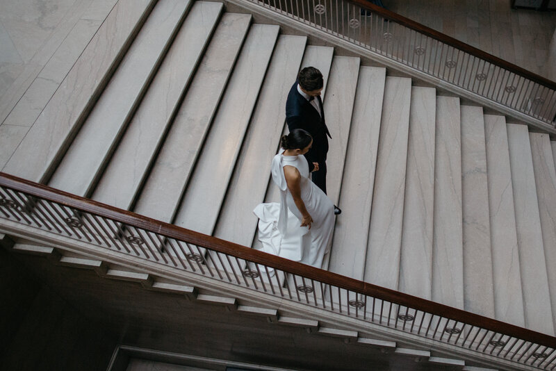Overhead image of bride and groom holding hands walking down steps of art museum in Chicago
