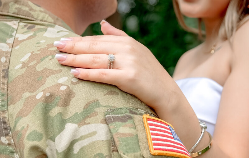 Close-up of engagement ring on hand resting on military uniform during engagement session at La Gloria in Austin, Texas.