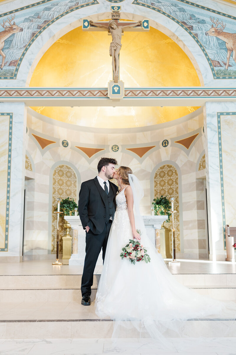 bride and groom kissing in a Catholic church