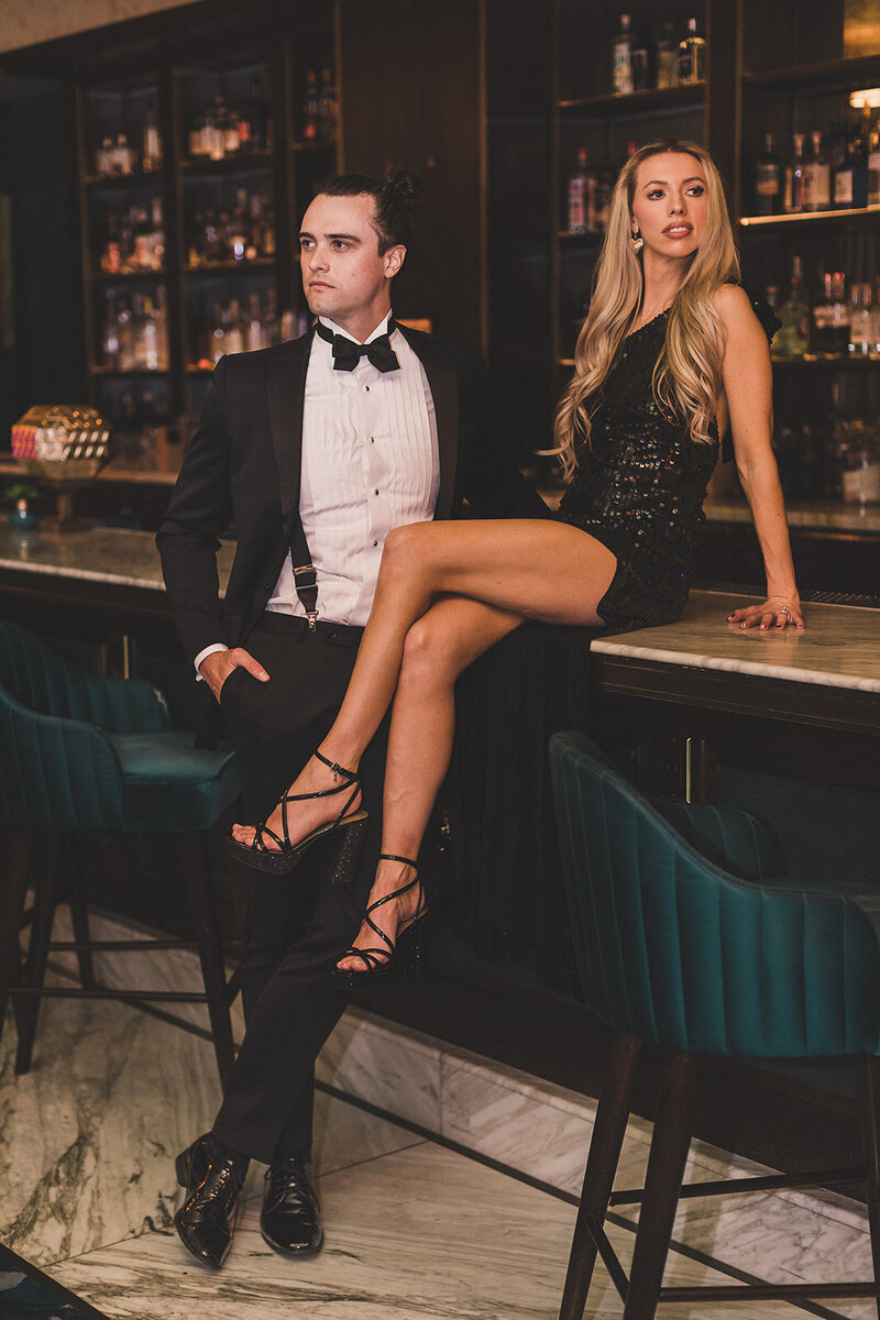 couple sits on bar during las vegas engagement photo session