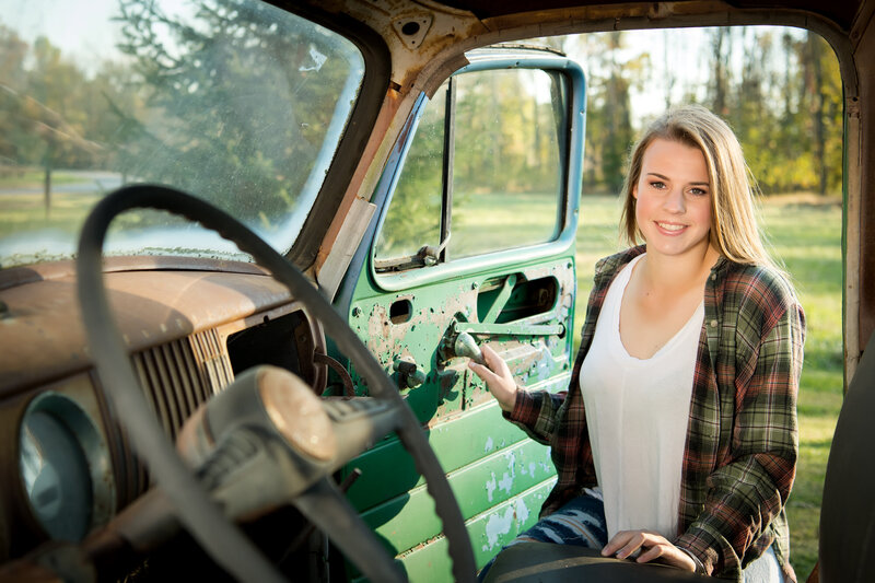 senior girl with flannel shirt in doorway of vintage truck