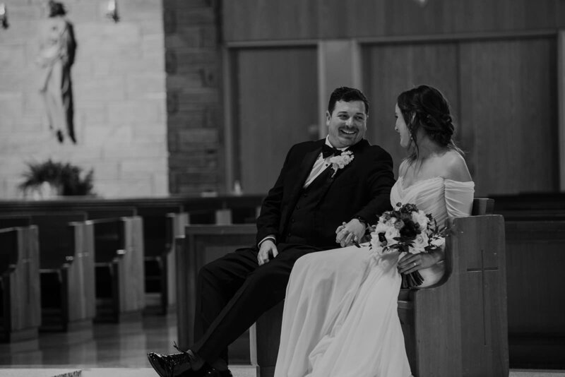 A newlywed couple sitting in a pew together