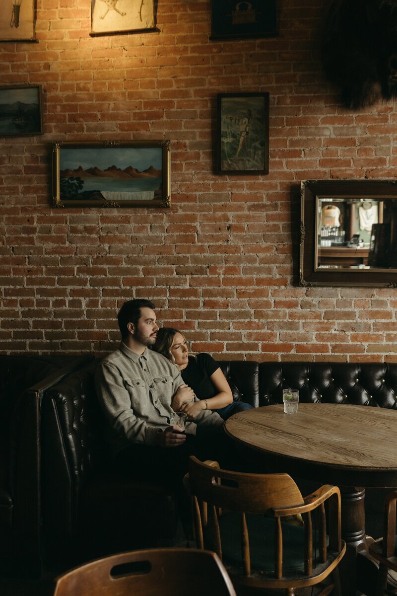 Engaged couple embrace in downtown Boise bar, Pengilly Saloon by destination wedding photographer Erica Rochelle Photography