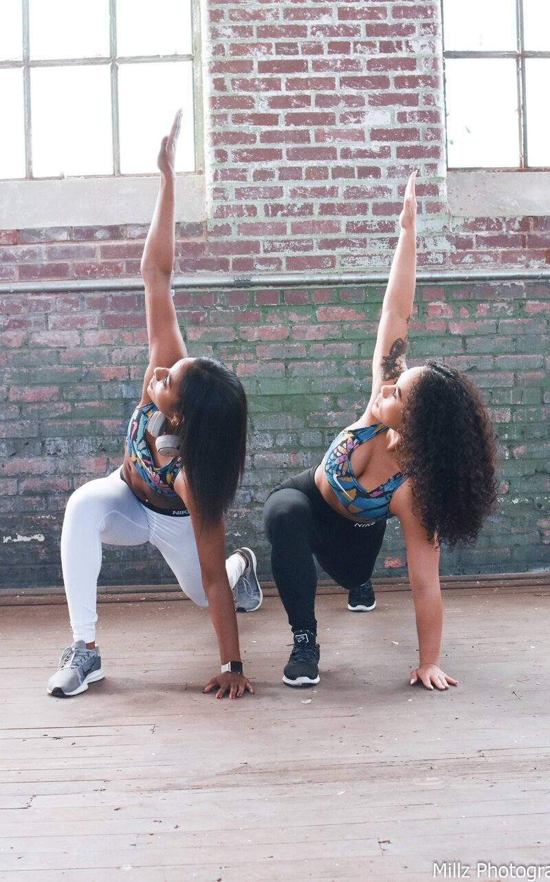 two women engaging in a yoga pose inside of a studio photographed by Millz Photography in Greenville, SC