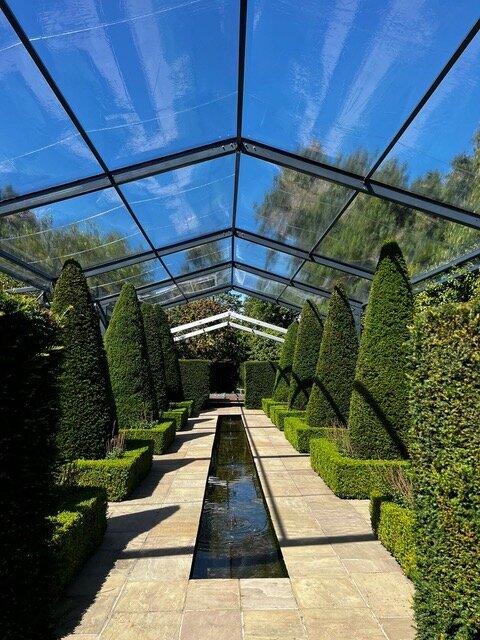 A very large frame marquee with hedges in front of it