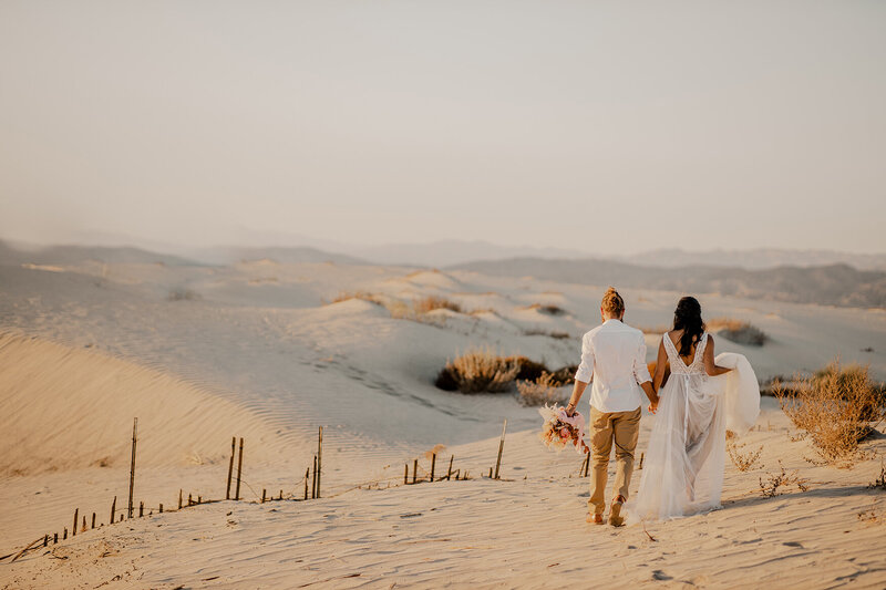 couple walks through sand