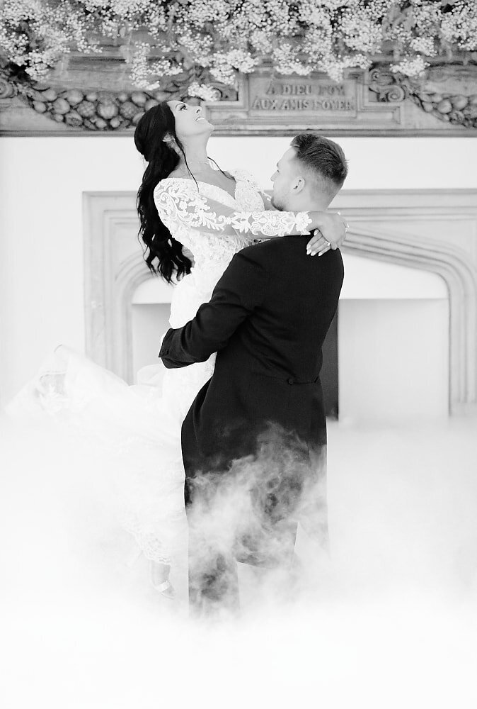 groom lifting his bride into the air surrounded by dry ice during their fist dance