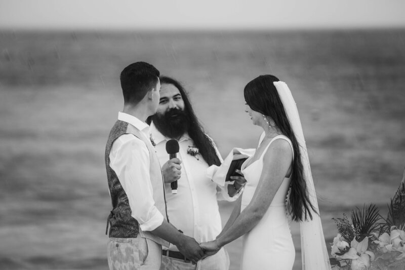 A beach wedding ceremony where a bride and groom exchange vows in front of the ocean.