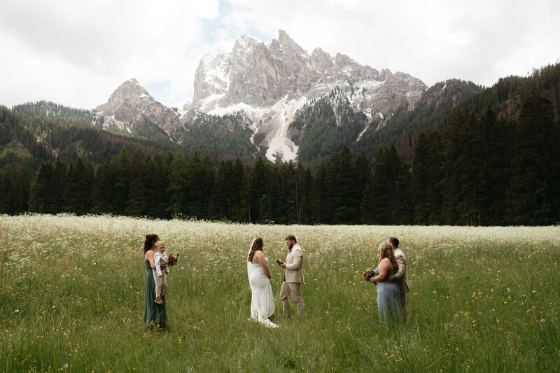 Bride and groom and 4 guests stand in an alpine meadow as they Get Married in the Dolomites as Foreigners