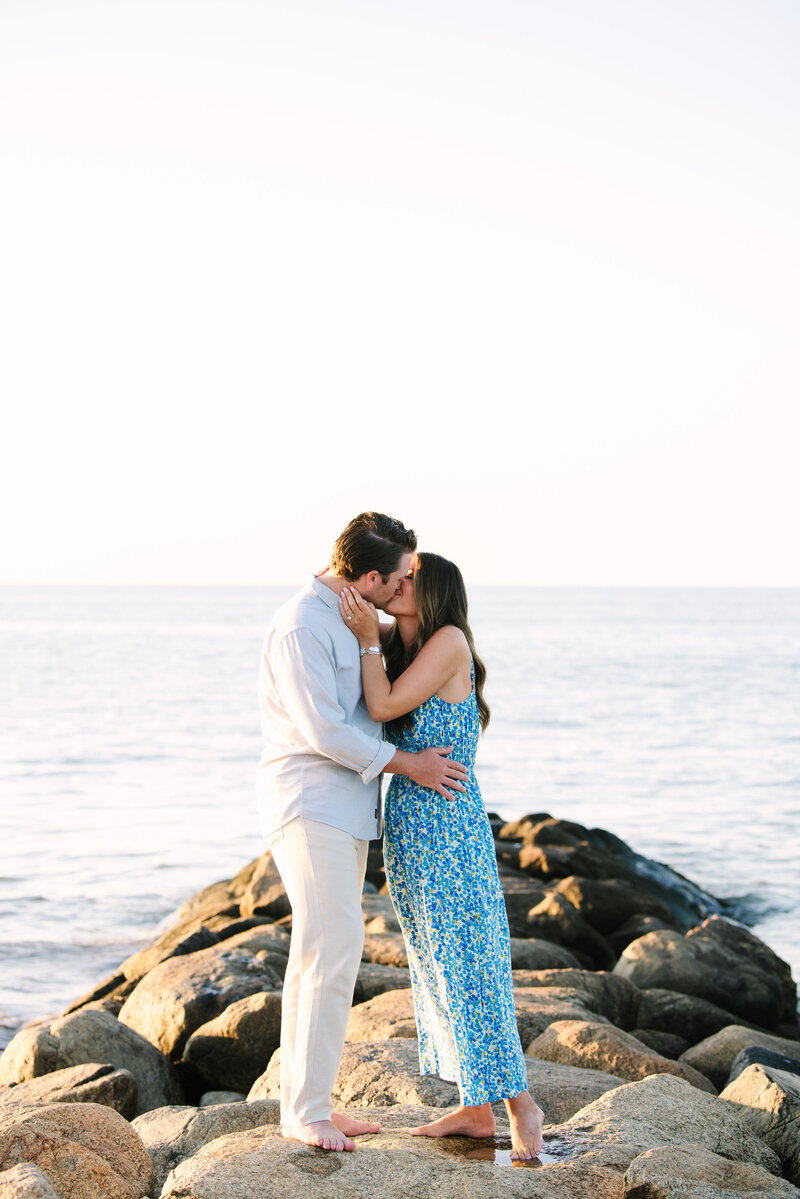 newly engaged couple kissing on the beach at point of rocks landing beach in brewster massachusetts