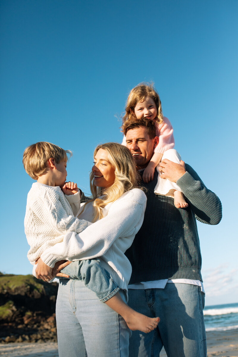 A family cuddle close in the setting sun at Cabarita Beach .Norries Headland is in the background