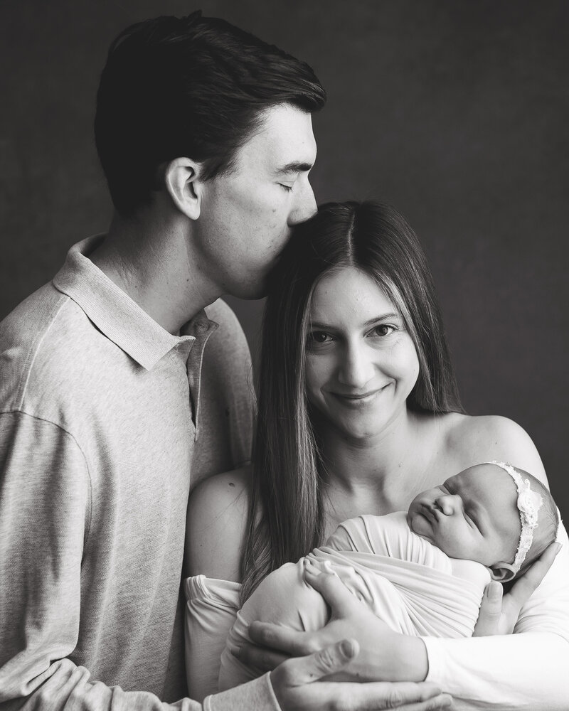 Mom and Dad hold their newborn daughter for their newborn family session in murrysville.
