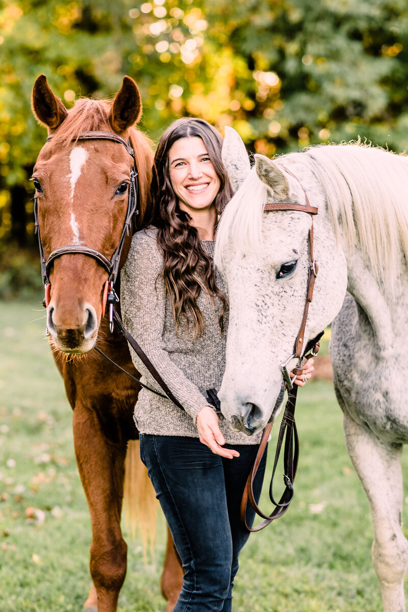 Woman standing between chesnut and grey white horse by Michigan Equine photographer Stephanie Anne
