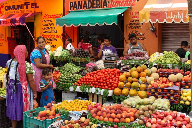 A colorful produce stall with women in traditional dress at a market near Oaxaca, Mexico ©Stephanie Dosch | theViatrix Luxury Travel