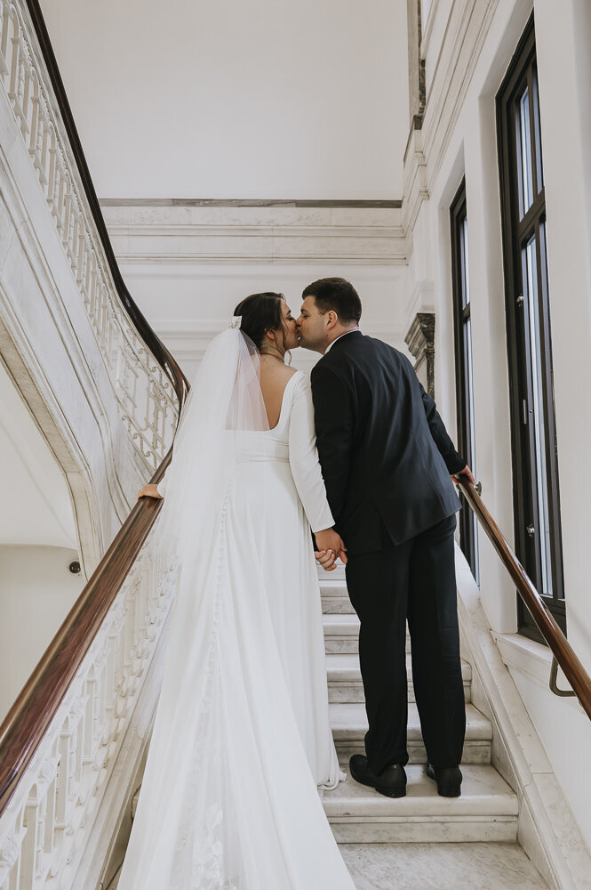a bride and groom kissing in a stairwell