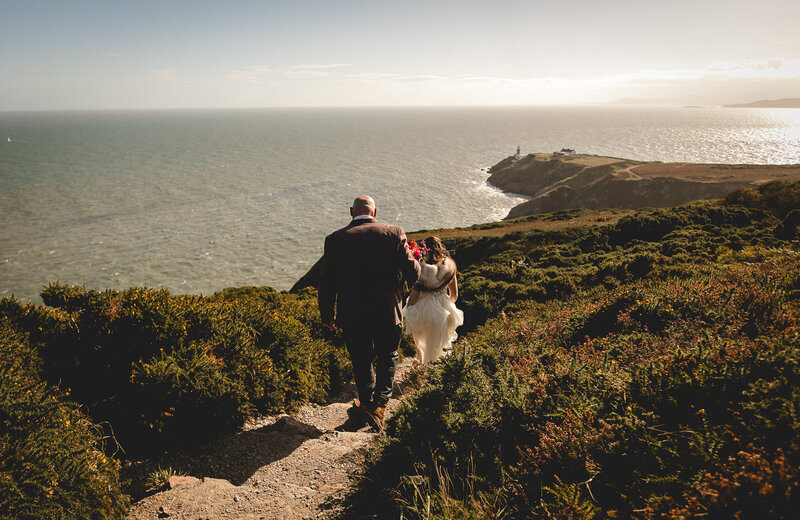 Bride and groom walking at Howth Cliff Walk for their micro wedding  in Dublin, Ireland