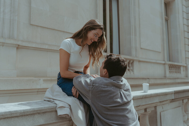 couple sitting on ledge outside of the Met during NYC engagement photos, captured by Elsie Goodman, an NYC engagement and couples photographer