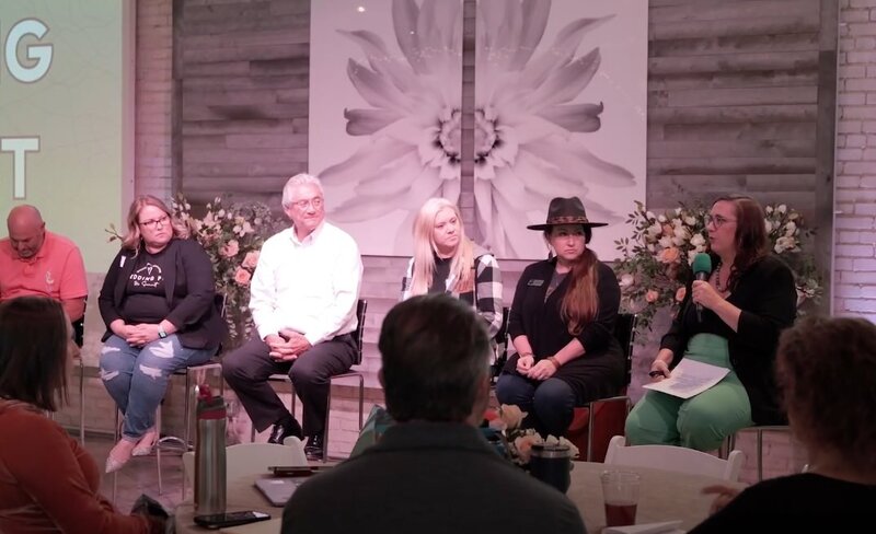 A group of people on a stage talking at a conference 