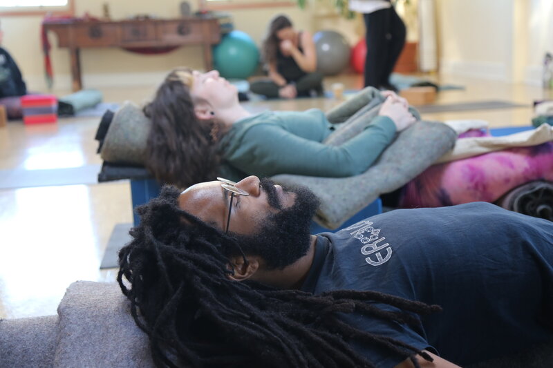 Student in a restorative yoga pose enjoying a moment of deep rest during Soma Yoga Institute’s therapeutic yoga certification program