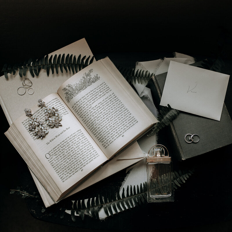 bride's details with statemetn earrings, rings, vows, and her favorite book