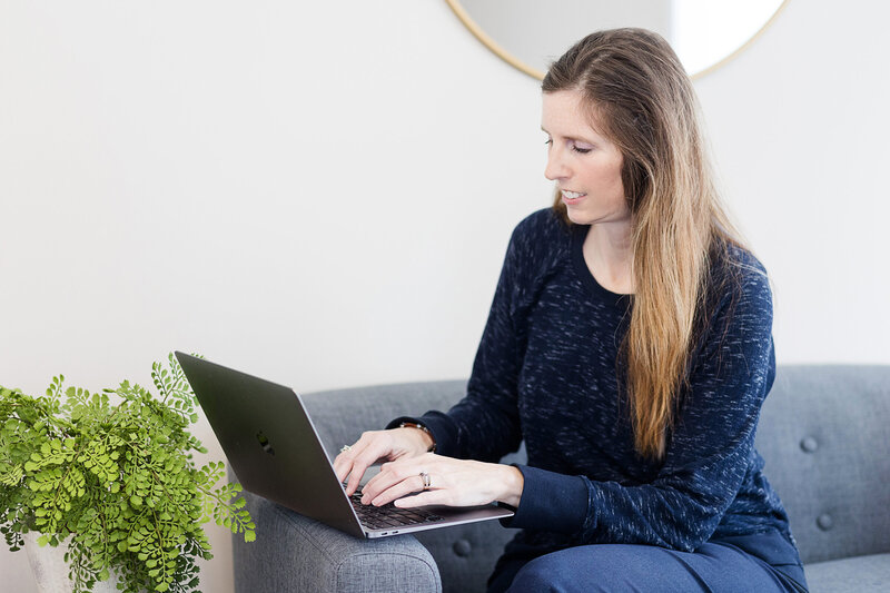 Heather sitting on a couch with her laptop