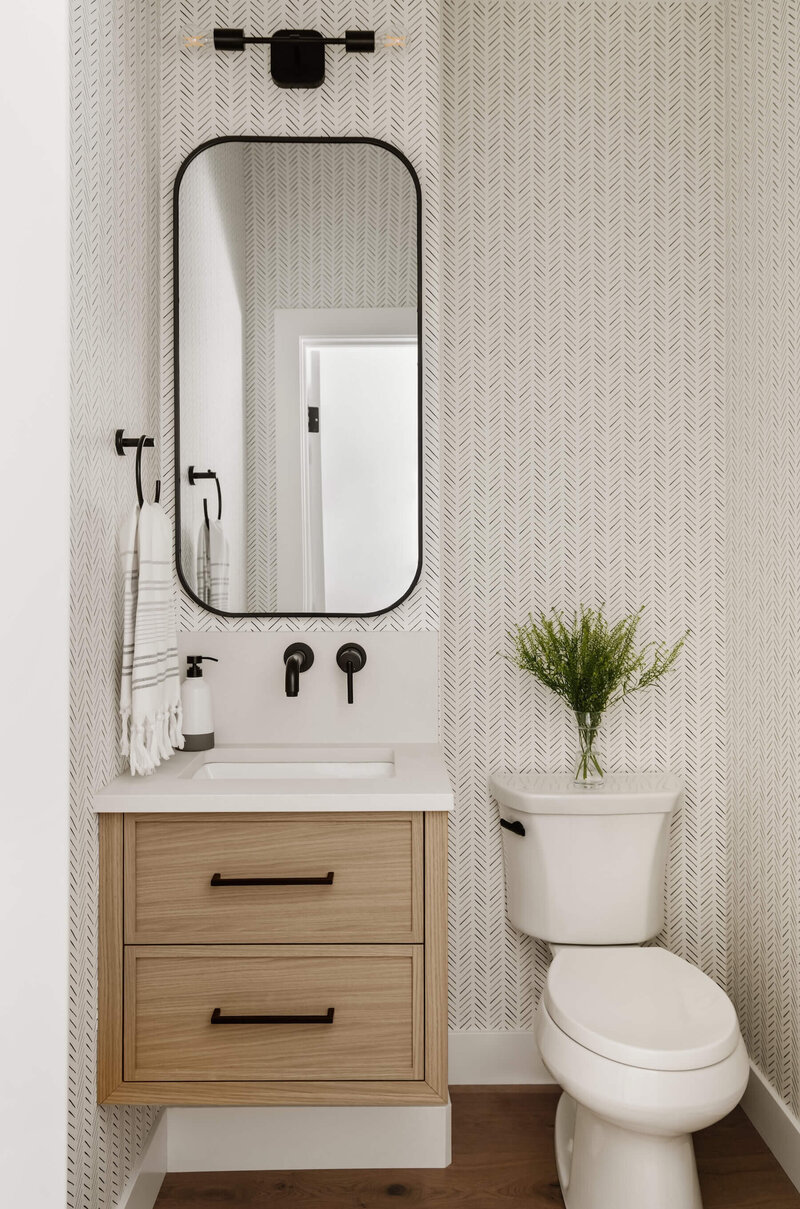 Powder room with geometric wallpaper, black accents and white oak vanity. 