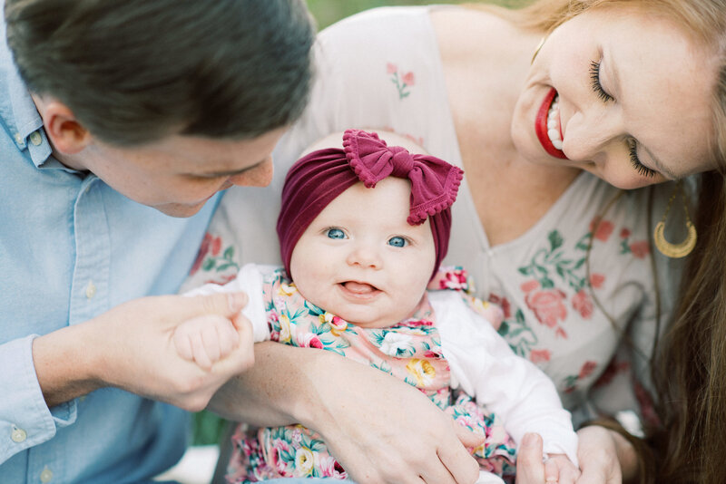 Little girl being looked down on by parents while wearing a maroon bow headband