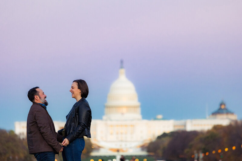 A couple laughs together with the US Capitol in the background.