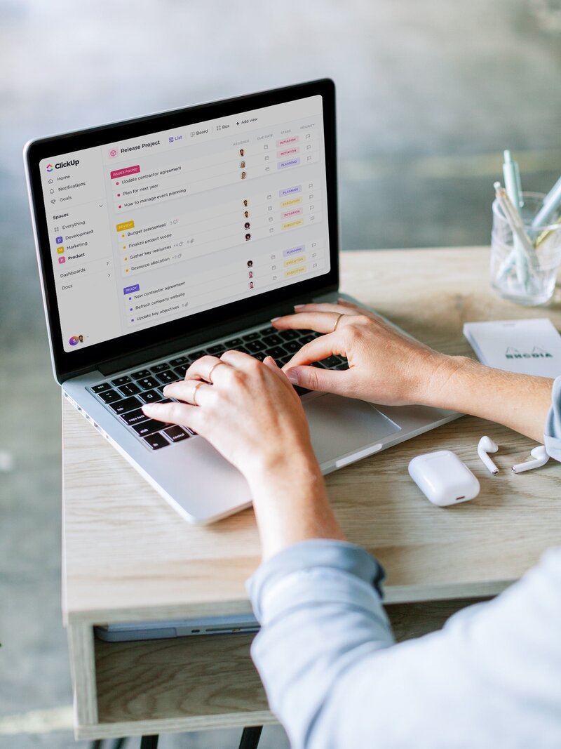A close-up of hands working on a laptop with ClickUp open—showcasing streamlined project management and system setup services.