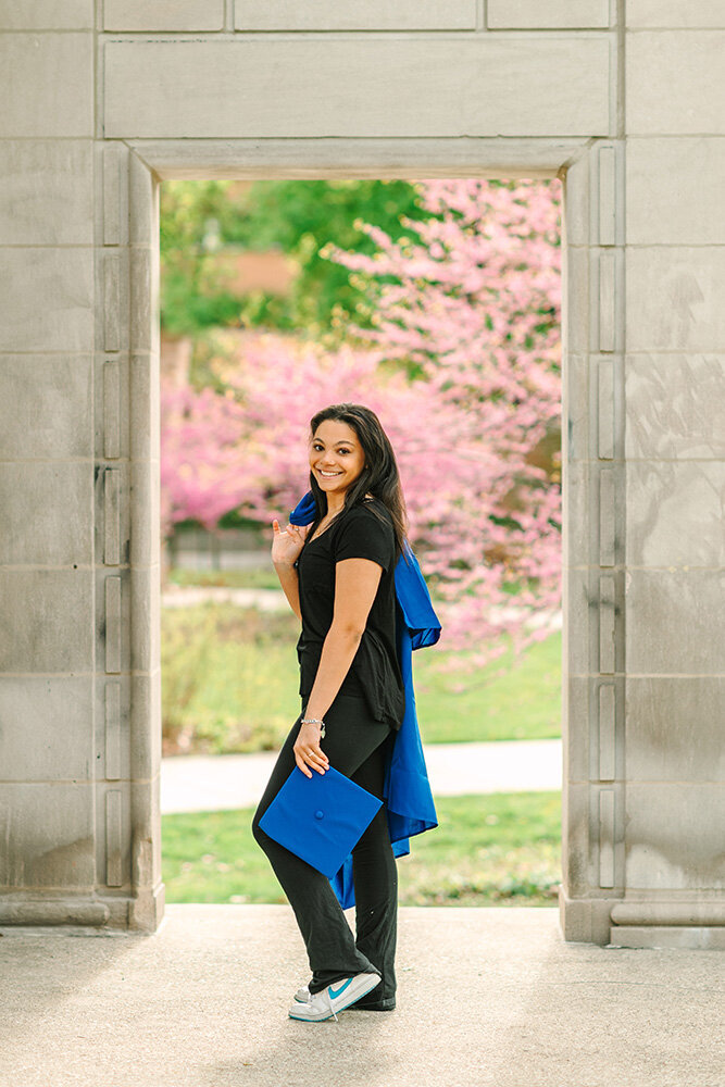 Oak Park-River Forest High School graduate holding her cap and gown in front of a redbud tree