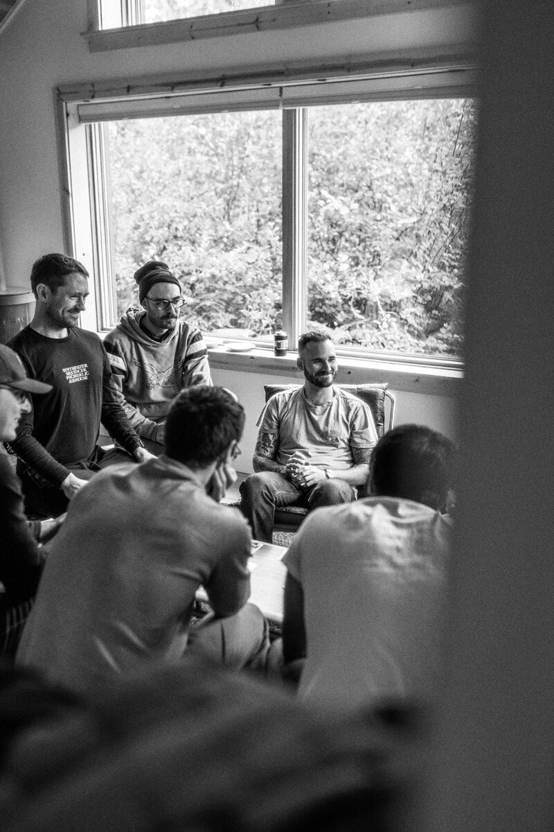 A group of men playing board games, captured through a window pane, representing the candid , documentary style of wedding photography by Among the Oaks. 