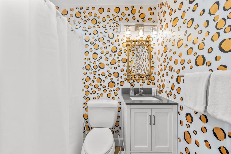 Bold bathroom design at Tropical House featuring leopard-print wallpaper, gold-framed mirror, and modern sink—perfect for Instagram!